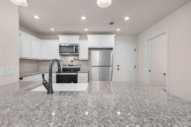 a kitchen with granite countertop a refrigerator and a sink