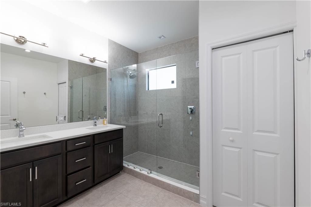 7510 Rockefeller Drive Naples, FL 34119 - Photo 25 of 31 Full bath featuring double vanity, a stall shower, a closet, and light tile patterned floors