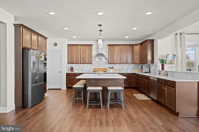 a kitchen with stainless steel appliances granite countertop a kitchen island hardwood floor sink and stove