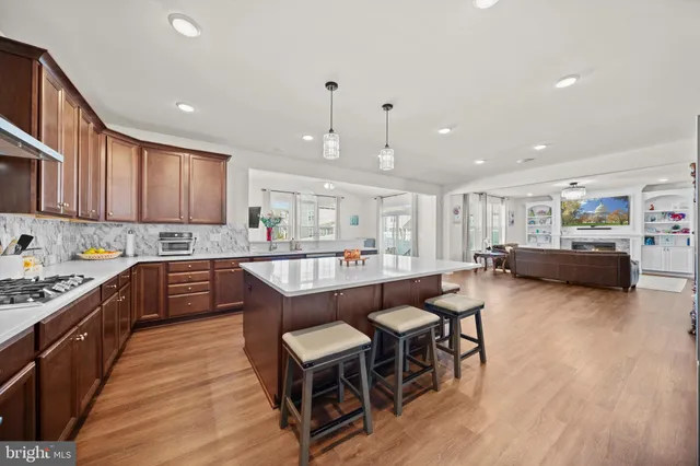 a kitchen with stainless steel appliances granite countertop wooden floors a stove a sink and a refrigerator