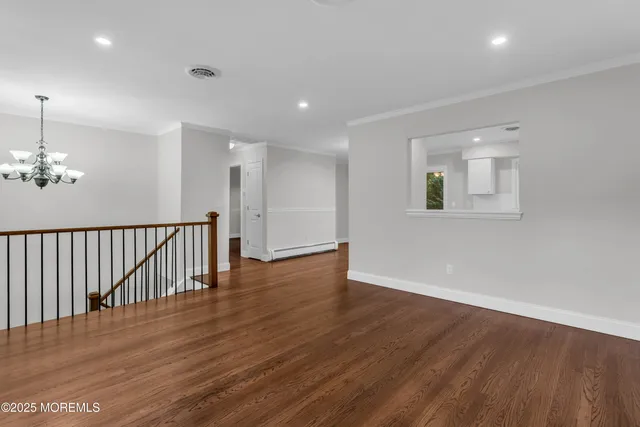 an empty room with wooden floor chandelier and windows