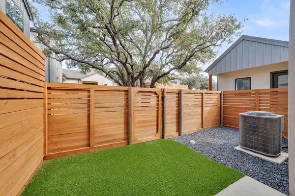 a view of a backyard with wooden fence and a large tree