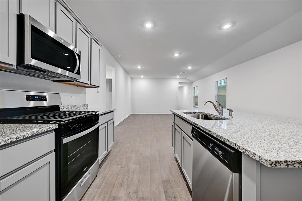 295 Evergreen Sumac Loop Kyle, TX 78640 - Photo 11 of 30 Kitchen featuring stainless steel appliances, light stone counters, recessed lighting, light wood-style flooring, and a kitchen island with sink