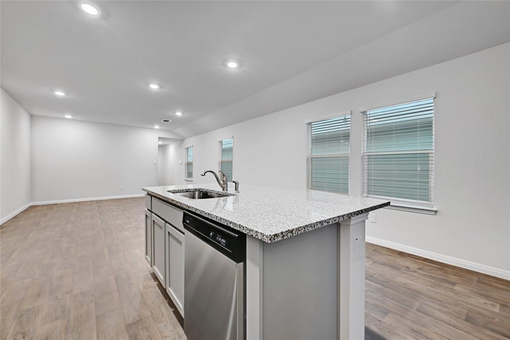 295 Evergreen Sumac Loop Kyle, TX 78640 - Photo 10 of 30 Kitchen featuring dishwasher, light wood-type flooring, a center island with sink, light stone countertops, and recessed lighting