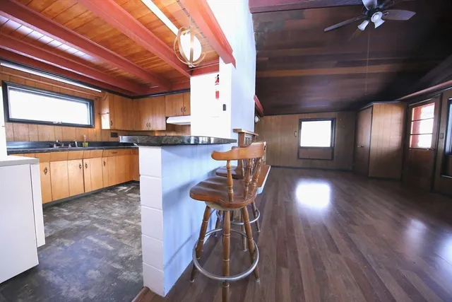 a view of an empty room with wooden floor and a kitchen