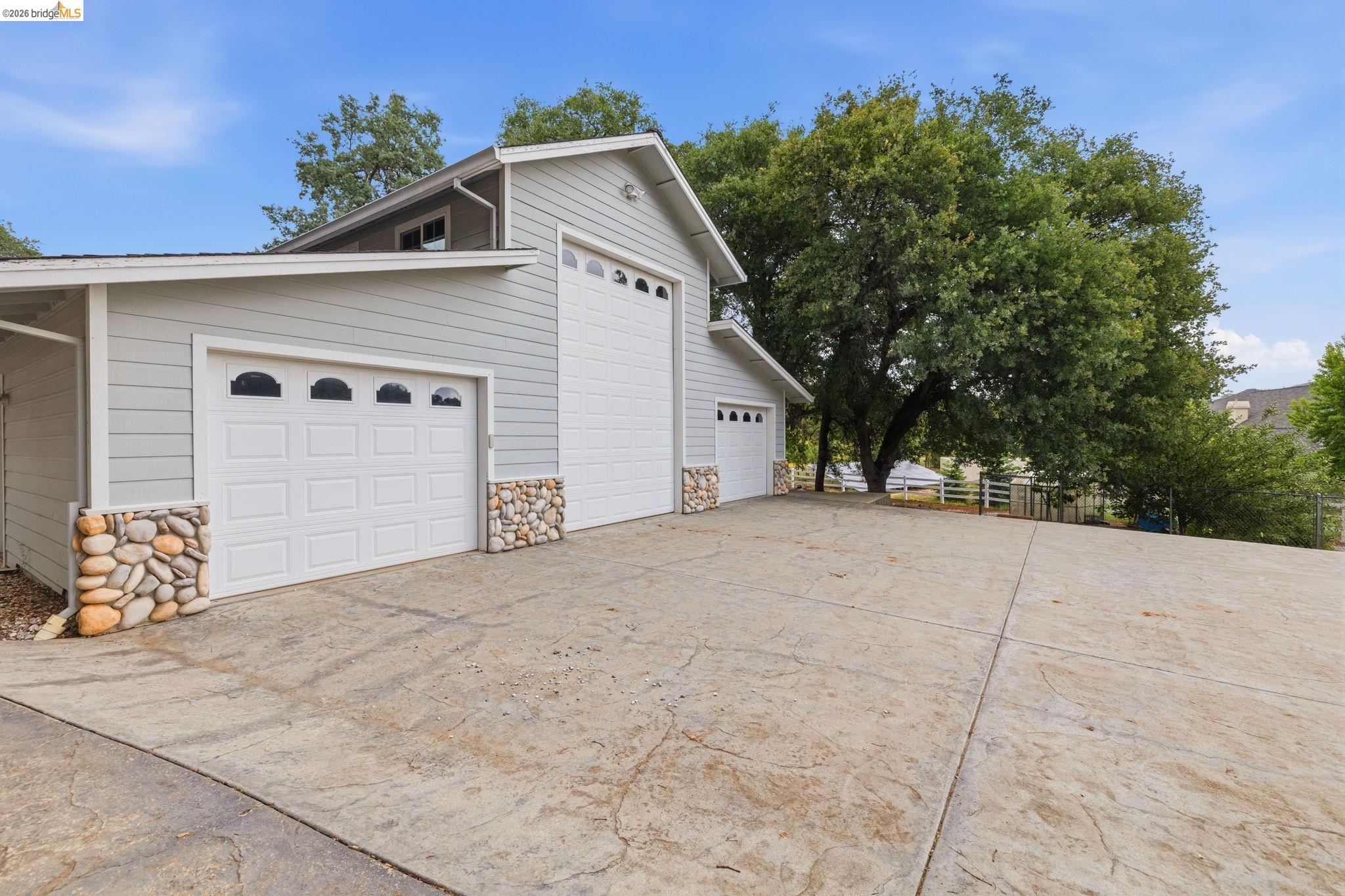 18450 Lambert Lake Road Sonora, CA 95370 - Photo 75 of 87 Multi-bay garage with light gray siding and natural stone accents