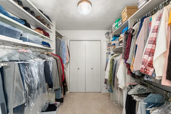a view of walk in closet with clothes and shoes