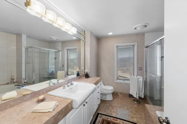 a bathroom with a granite countertop sink a toilet a mirror and shower