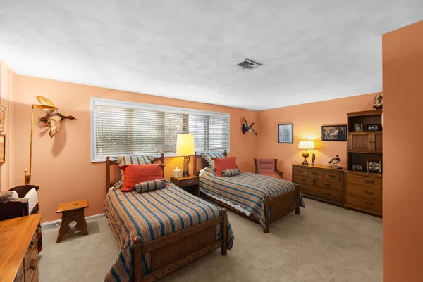 a bedroom with two beds and a dresser next to a window