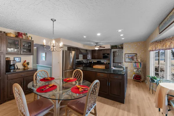 a kitchen with stainless steel appliances kitchen island granite countertop a dining table chairs and a refrigerator