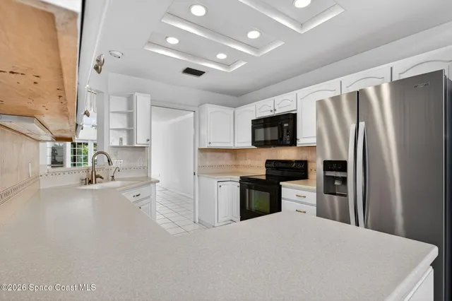 an empty room with wooden floor chandelier fan and windows