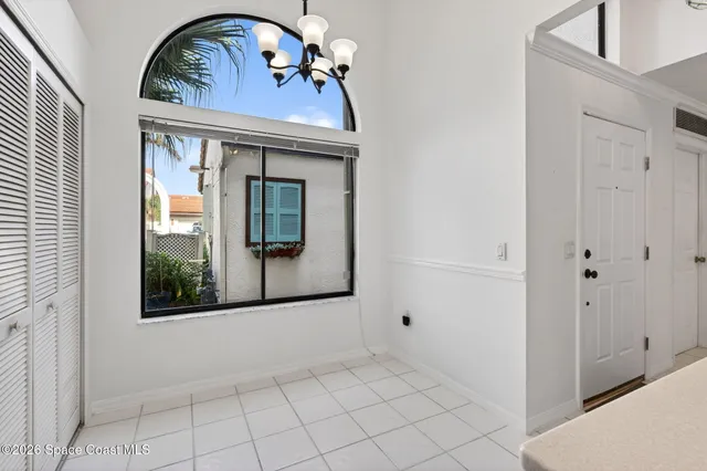 an empty room with wooden floor chandelier fan and windows