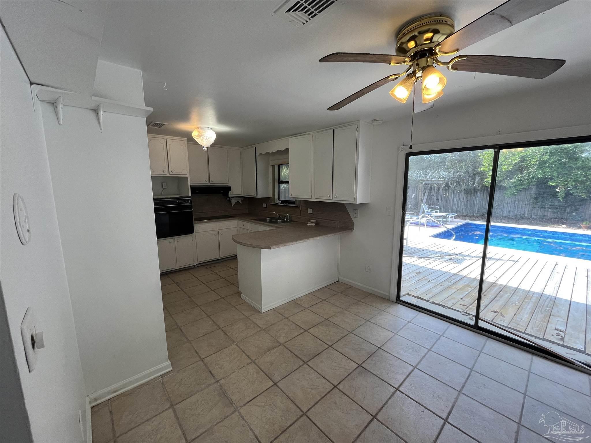 4511 St Nazaire Road Pensacola, FL 32505 - Photo 7 of 21 a kitchen with granite countertop a refrigerator a sink and white cabinets