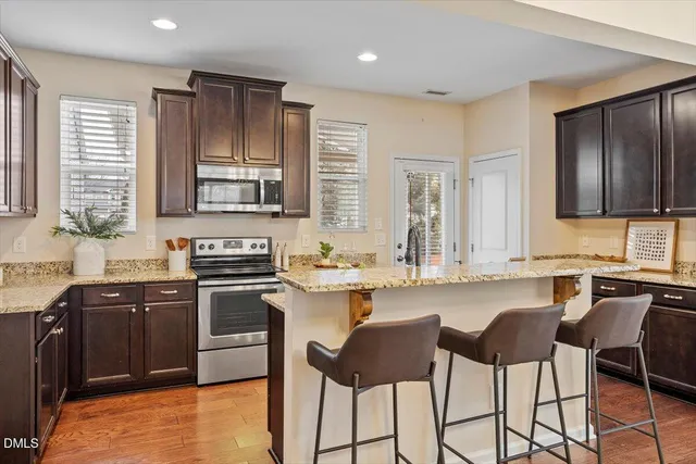 a kitchen with granite countertop stainless steel appliances stove microwave refrigerator and sink