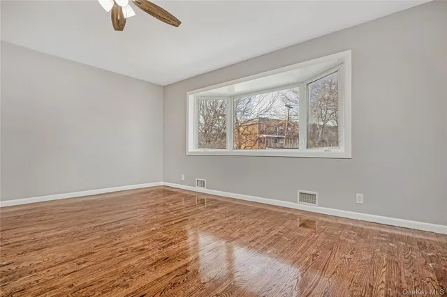 a view of an empty room with window and wooden floor