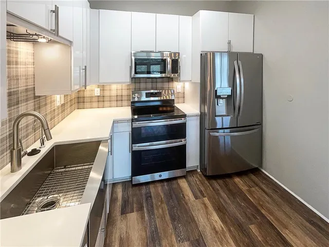 a kitchen with granite countertop stainless steel appliances a refrigerator and microwave