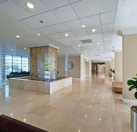 a large hall with stainless steel appliances granite countertop a large counter top a refrigerator and a sink