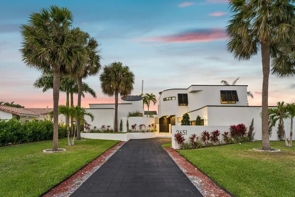 a front view of a house with a garden and palm tree
