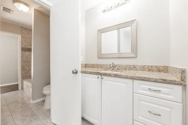 a bathroom with a granite countertop sink and a toilet