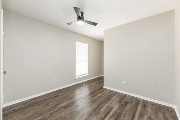 an empty room with wooden floor chandelier fan and windows