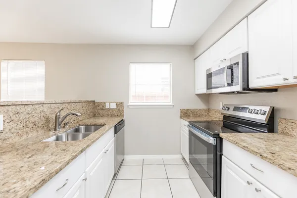 a kitchen with granite countertop a sink stove and cabinets