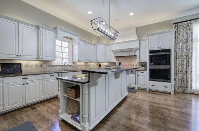 a kitchen with kitchen island granite countertop a sink cabinets and stainless steel appliances