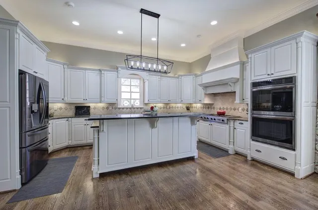 a kitchen with stainless steel appliances granite countertop a stove and a white cabinets
