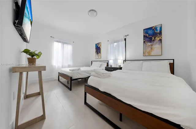 a bedroom with a bed a painting on the wall and a potted plant