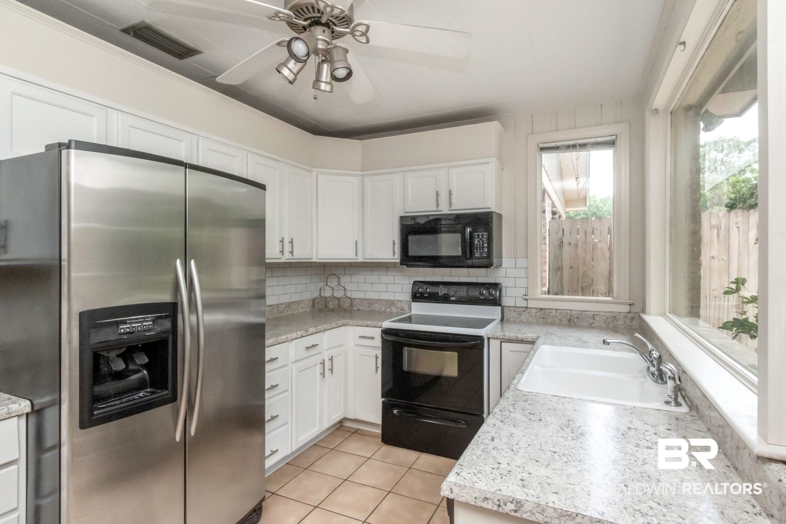 1906 Old Shell Road Mobile, AL 36607 - Photo 8 of 26 Kitchen featuring white cabinetry, ceiling fan, sink, range with electric stovetop, and stainless steel fridge