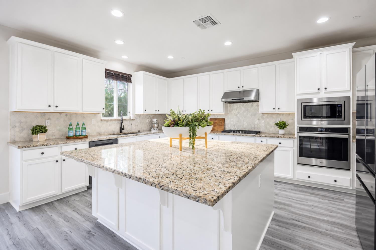 1837 South La Barbera Avenue Mountain House, CA 95391 - Photo 16 of 54 a kitchen with stainless steel appliances granite countertop a stove top oven a sink dishwasher and white cabinets with wooden floor