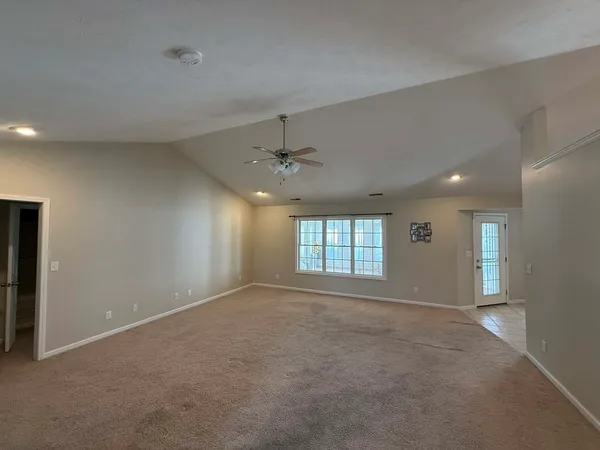 an empty room with windows and ceiling fan
