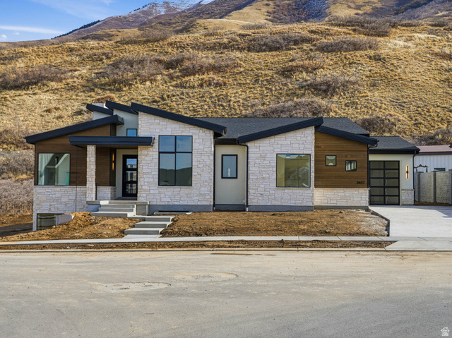 3457 South Cobblestone Loop Mapleton, UT 84664 - Photo 1 of 1 Modern home featuring stone siding, a mountain view, driveway, a garage, and a porch