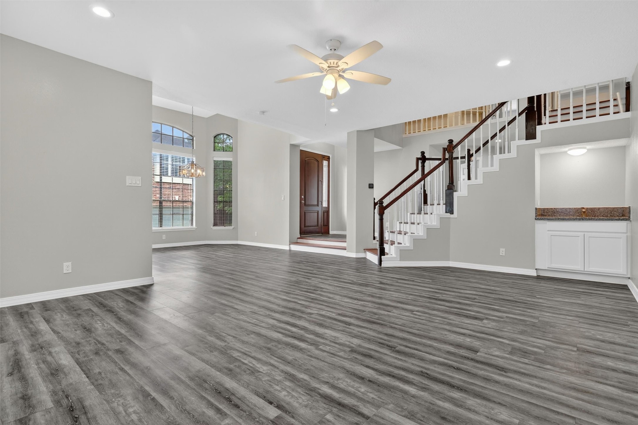 12929 Kingsbridge Lane Houston, TX 77077 - Photo 9 of 42 Welcome into this expansive open-concept living space featuring soaring ceilings, elegant architectural details, and a stunning staircase that creates a true grand entrance. The oversized living area offers endless possibilities for entertaining, relaxing, or designing your dream interior. Buyers will love the modern luxury-style flooring, abundant natural light, neutral designer paint, and spacious flowing layout. Large windows and high ceilings create a bright, airy atmosphere that feels both warm and sop