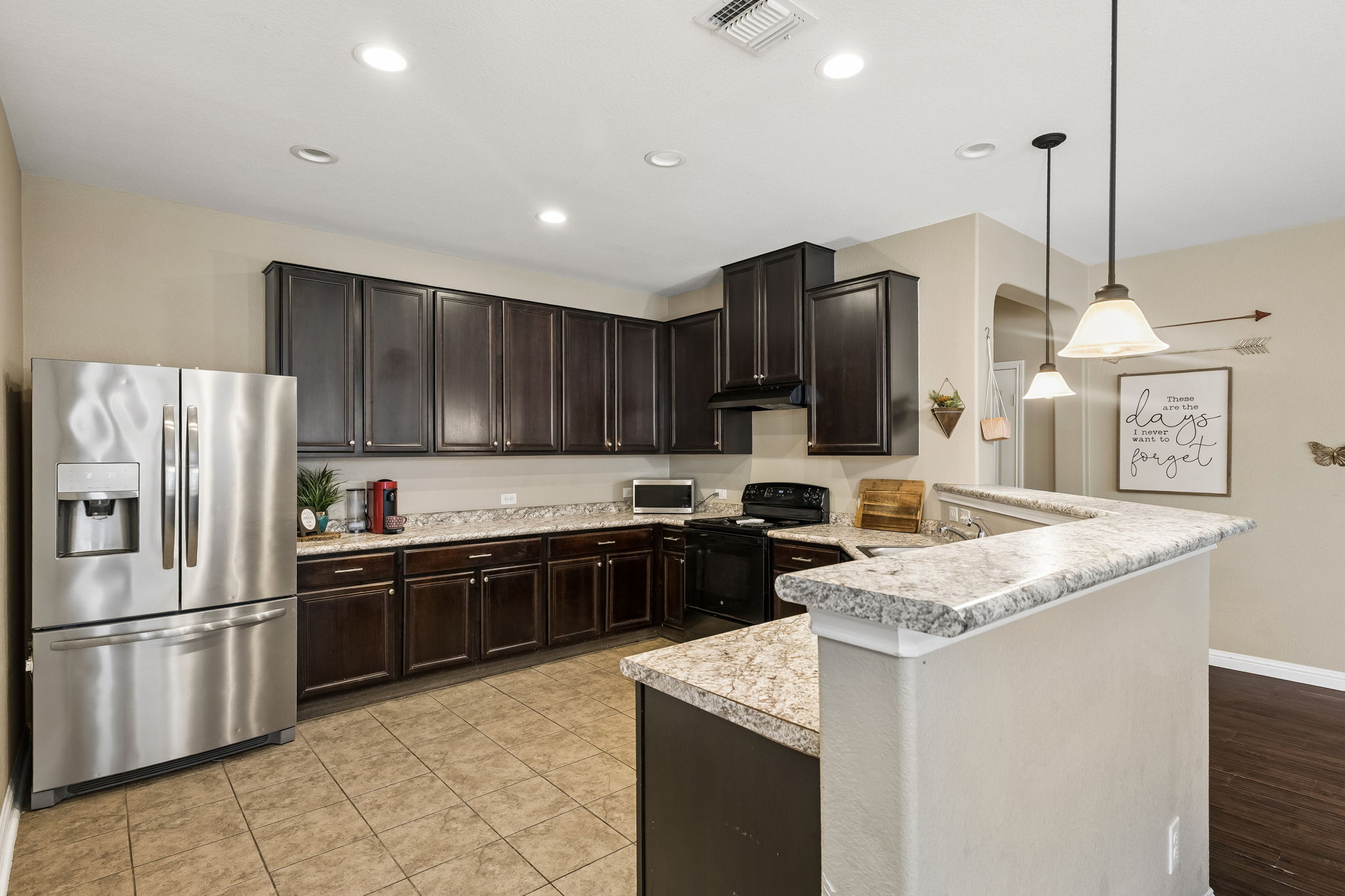 1113 Yellow Iris Road Leander, TX 78641 - Photo 8 of 26 Rich dark cabinetry pairs beautifully with stone-look countertops and classic tiled flooring.
