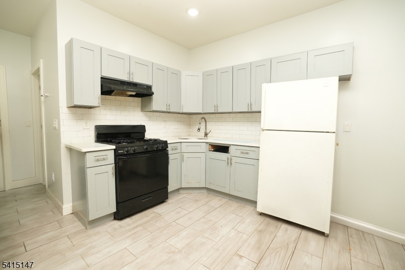 14 Hazel Place Newark, NJ 07108 - Photo 3 of 10 a kitchen with a sink a white refrigerator and a stove