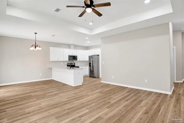 a view of kitchen with stainless steel appliances refrigerator stove and wooden floor