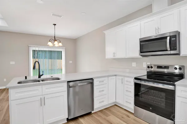 a kitchen with cabinets stainless steel appliances a sink and a wooden floor