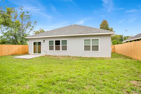 a white house that has a small yard and wooden fence