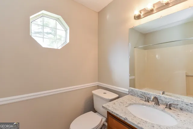 a bathroom with a granite countertop toilet sink and mirror