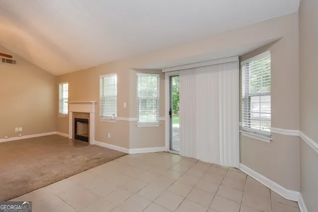 an empty room with windows and fireplace