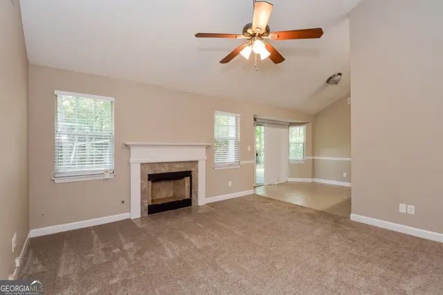 a view of an empty room with chandelier fan and fire place