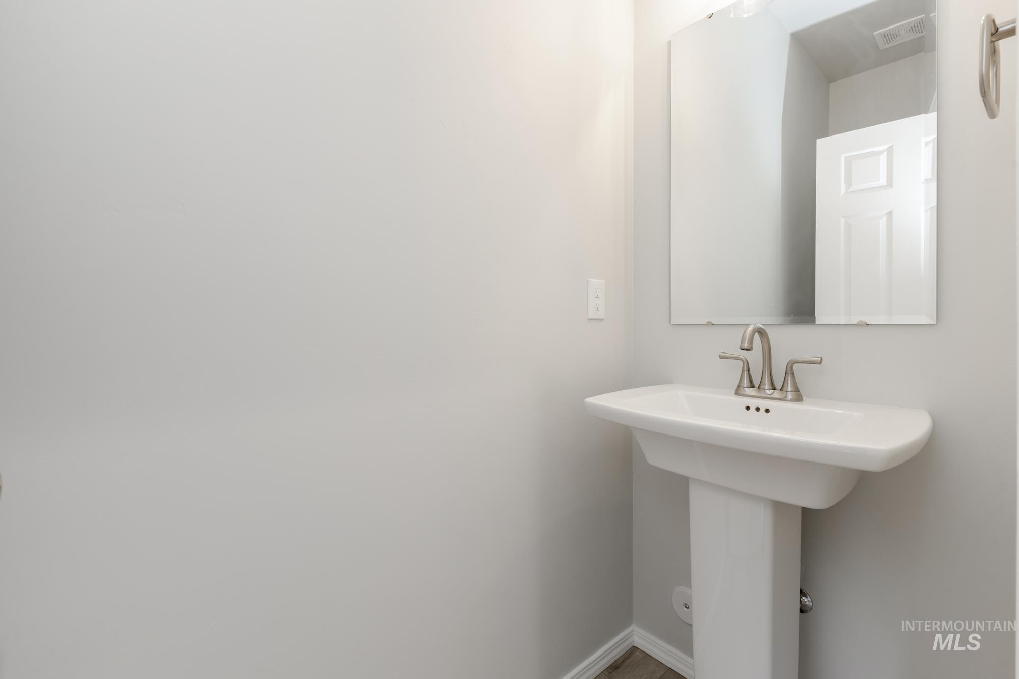 12842 Ropers Street Nampa, ID 83651 - Photo 14 of 29 Pedestal sink with brushed nickel faucet, framed by a rectangular mirror