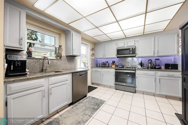 a kitchen with cabinets appliances a sink and a window