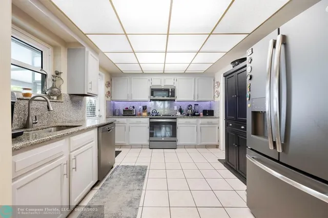 a kitchen with stainless steel appliances granite countertop a refrigerator a sink dishwasher a stove and white cabinets