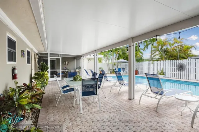 a view of a patio with table and chairs potted plants with floor to ceiling window