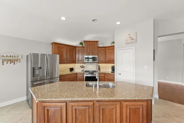 a kitchen with stainless steel appliances granite countertop a sink refrigerator and cabinets