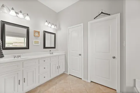 a spacious bathroom with double vanity a mirror and a shower