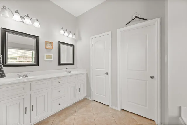 a spacious bathroom with double vanity a mirror and a shower