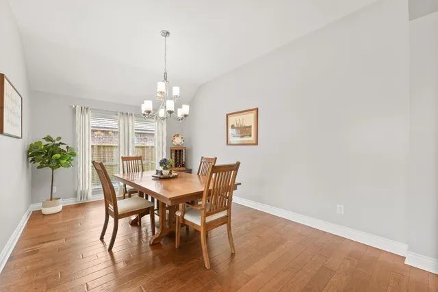 a dining room with furniture a chandelier and wooden floor