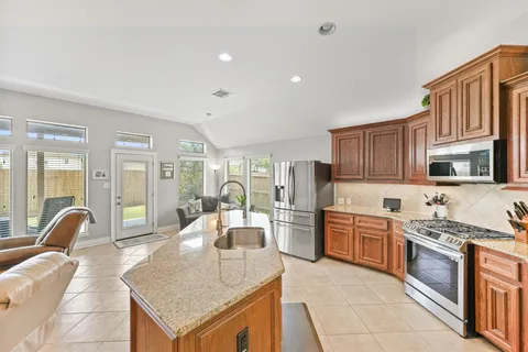 a large kitchen with stainless steel appliances granite countertop a stove top oven a sink dishwasher a dining table and chairs with wooden floor